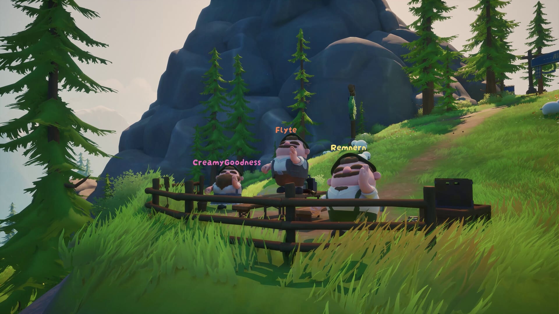 Three players dressed as farmers standing behind a wooden fence on a grassy hillside, a big blue-grey mountain behind them.